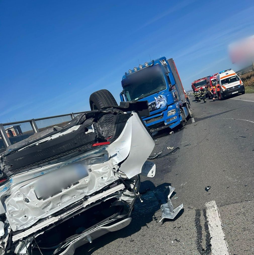 O mașină cu roțile în sus după impactul cu un camion